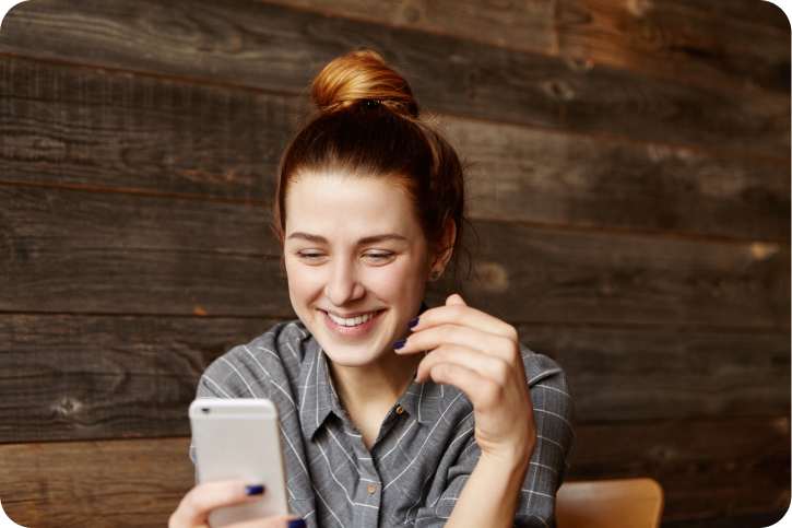 Woman smiling while looking at her smartphone.