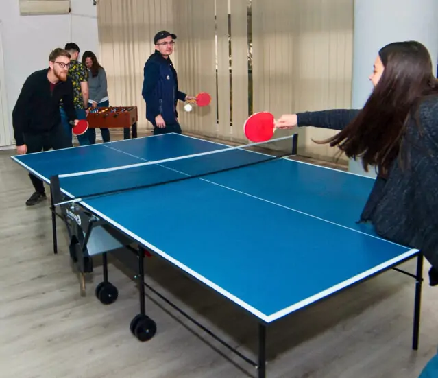 People engaged in a game of table tennis indoors.