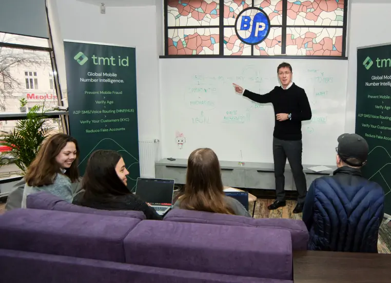 A presenter delivering a lecture to a small audience in a casual meeting space.