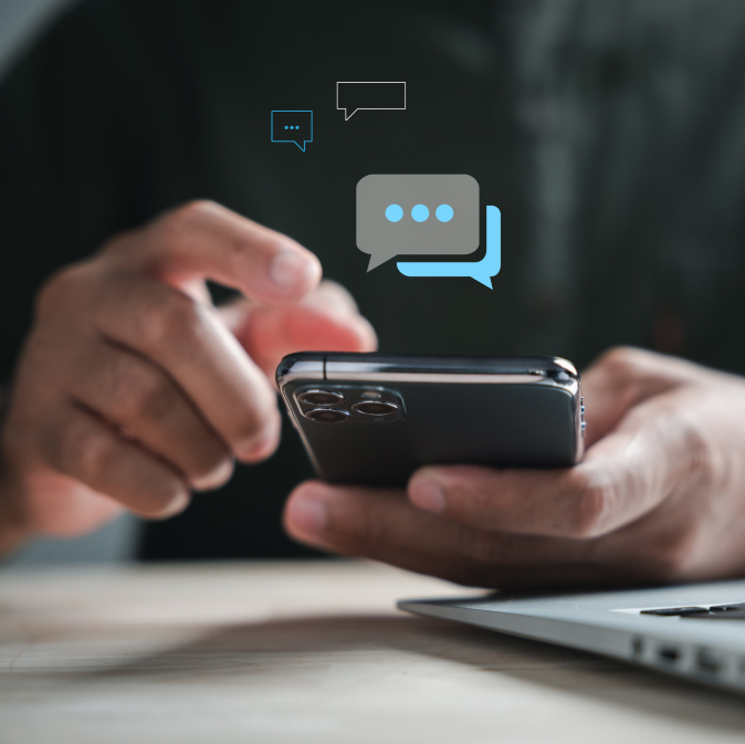 Una persona que envía mensajes de texto en un teléfono inteligente con íconos de burbujas de mensajes que indican comunicación digital.