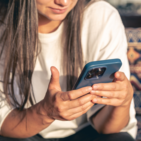 Mujer usando un teléfono inteligente con foco en sus manos y el dispositivo.